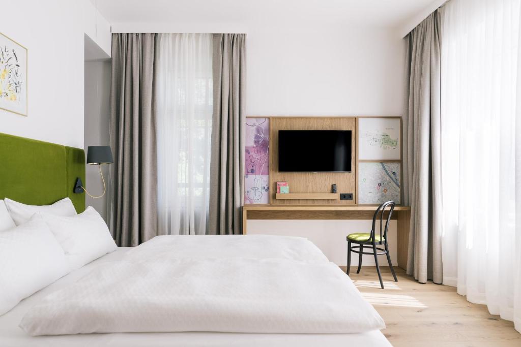 Schlafzimmer mit einem Bett und einem Schreibtisch mit einem TV in der Unterkunft Bio-Hotel Schani Wienblick in Wien