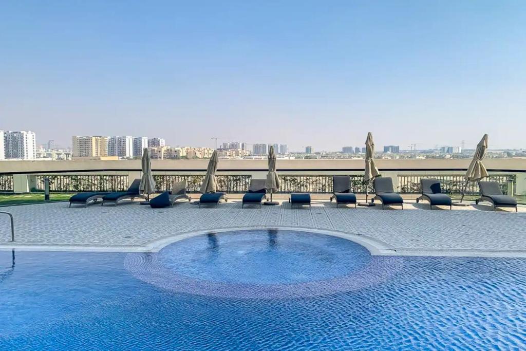 a swimming pool with chairs and umbrellas on a building at Studio in Al Furjan - Near Metro Dubai & Expo 2020 in Dubai