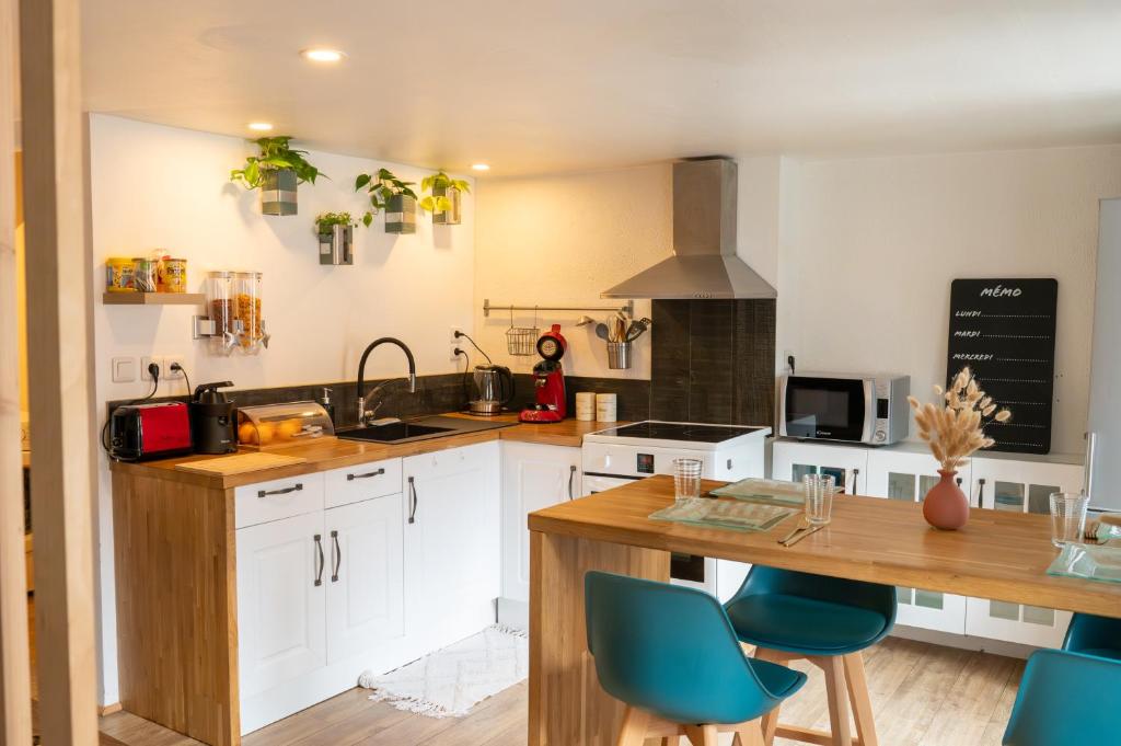 een keuken met witte kasten en blauwe stoelen bij Appartement au Centre ville historique Le vieux Langres in Langres