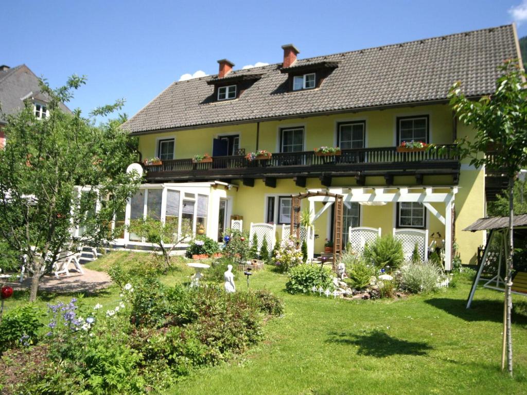 a yellow house with a balcony and a yard at Cozy Apartment in Feld am See near Ski Slopes in Feld am See