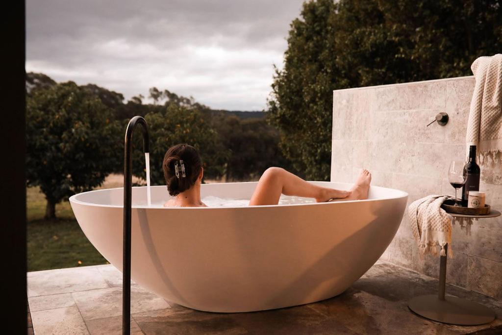 une femme assise dans une baignoire sur un patio dans l'établissement Carrajung Estate, à Willung South