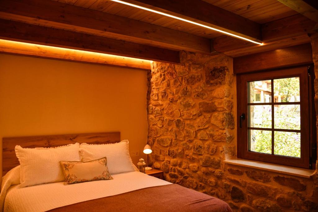 a bedroom with a bed with a stone wall at El Molino de Nocedo in León