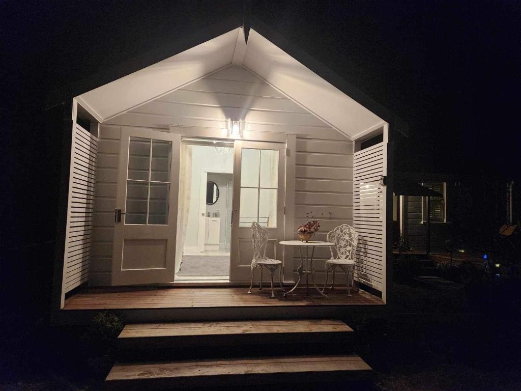 a small white house with a table and chairs at night at Petite on Regent in Martinborough 