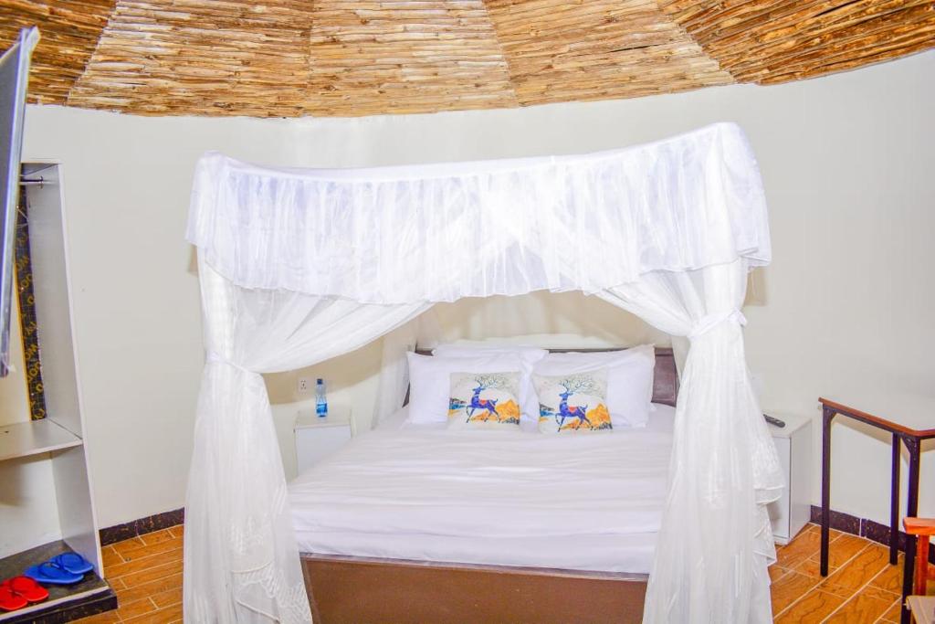1 dormitorio con cama blanca con dosel y almohadas en OLOIRIEN HOTEL & RESORT en Narok
