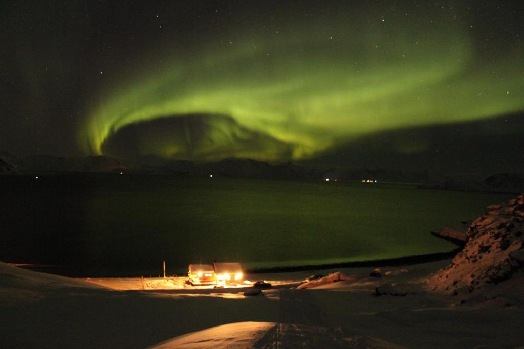 una aurora en el cielo sobre un cuerpo de agua en Nordmannsneset på Seiland en Hammerfest