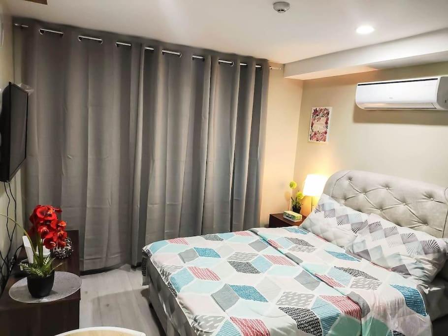 a bedroom with a bed and a window with curtains at Cityscape Grand Tower Condominium in Cebu City