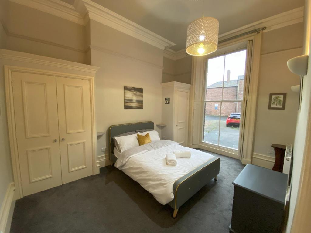 sypialnia z łóżkiem i dużym oknem w obiekcie MMR Flats w mieście Carlisle