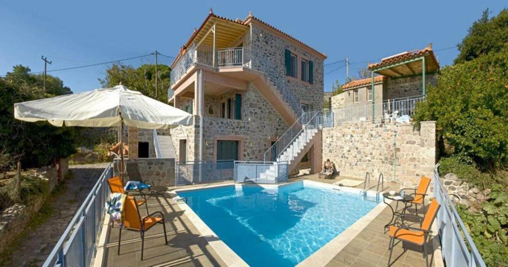 a house with a swimming pool with chairs and an umbrella at Petrini Krini Luxury Appartments in Ypsilométopon