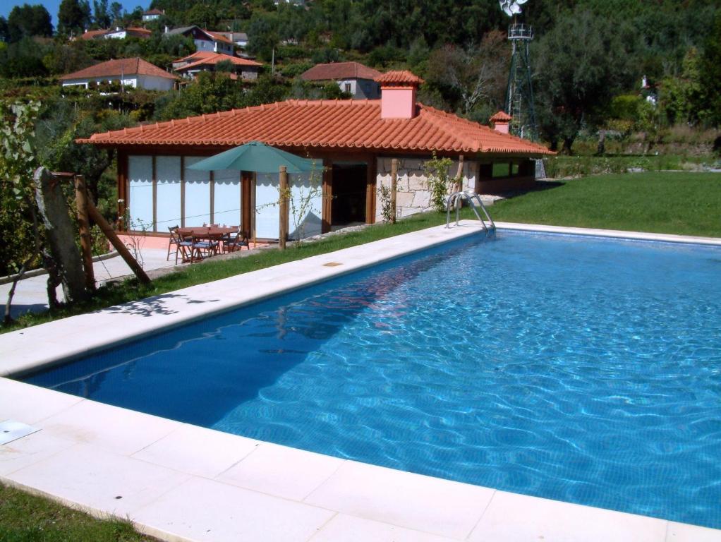 a swimming pool with a house in the background at Casa da Boa Fonte in Ponte de Lima