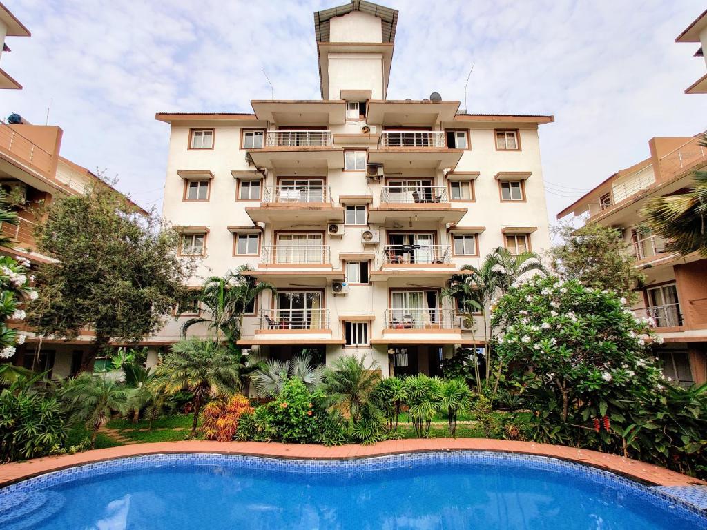 an apartment building with a swimming pool in front of it at Ivy Retreat- Serviced Apartments in Baga