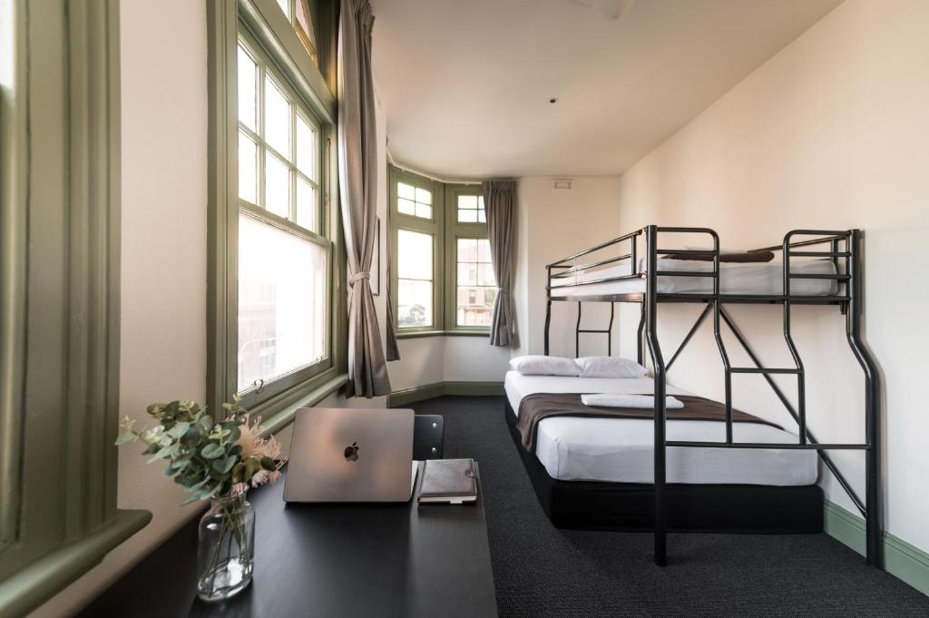 シドニーにあるシドニー セントラル インのベッドルーム1室(二段ベッド2台付)、床にノートパソコンが備わります。