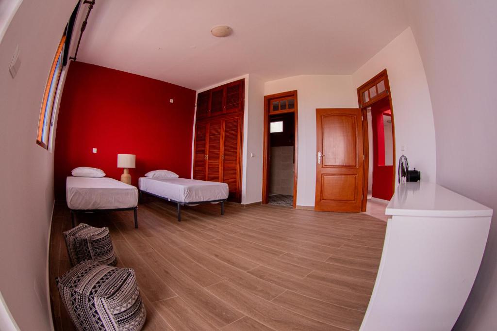 Cette chambre comprend 2 lits et un mur rouge. dans l'établissement Villa PalMarina, à Praia