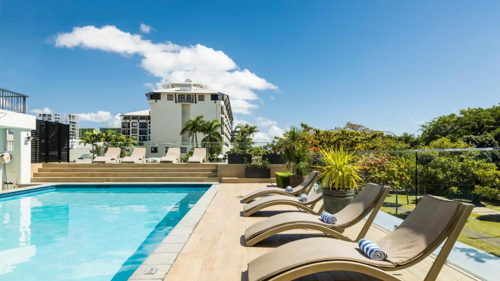 einen Pool mit Liegestühlen und ein Gebäude in der Unterkunft Pacific Hotel Cairns in Cairns