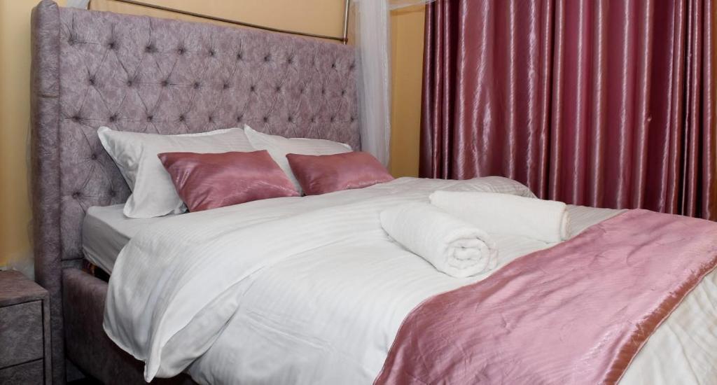 1 dormitorio con 1 cama grande con sábanas y almohadas blancas en Airport Bliss House, en Kisumu