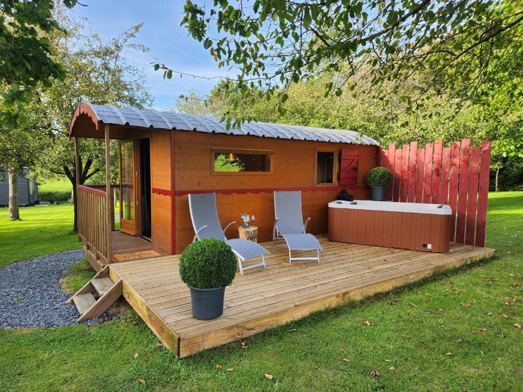 a small cabin with two chairs and a table on a deck at le cocon d'amour " Roulotte avec jaccuzi privé " in La Chapelle-du-Fest