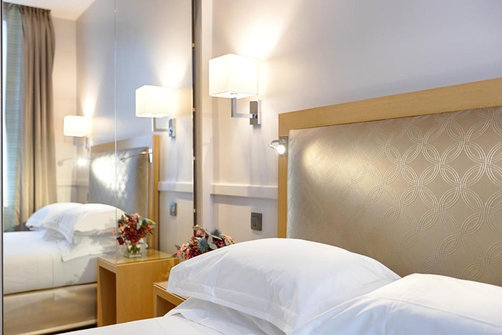 Habitación de hotel con 2 camas y espejo en Floride-Etoile en París