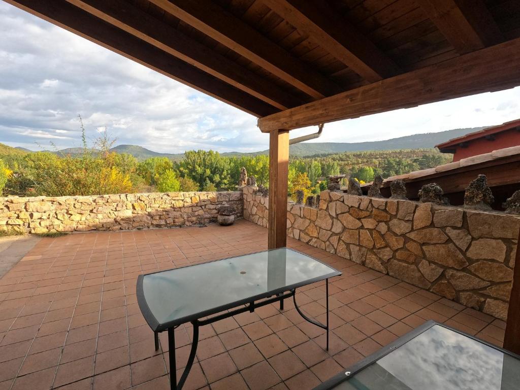 a glass table on a patio with a stone wall at Casa el Escalerón, #ExperienciasRurales in Uña