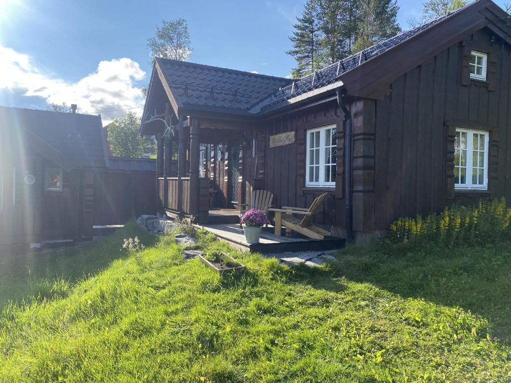 ein Blockhaus mit einer Veranda und einem Hof in der Unterkunft Hallingstue by Hallstensgaard - Geilo in Geilo