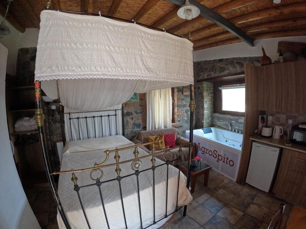 a bedroom with a canopy bed and a tub at AgroSpito Traditional Guest House in Agros
