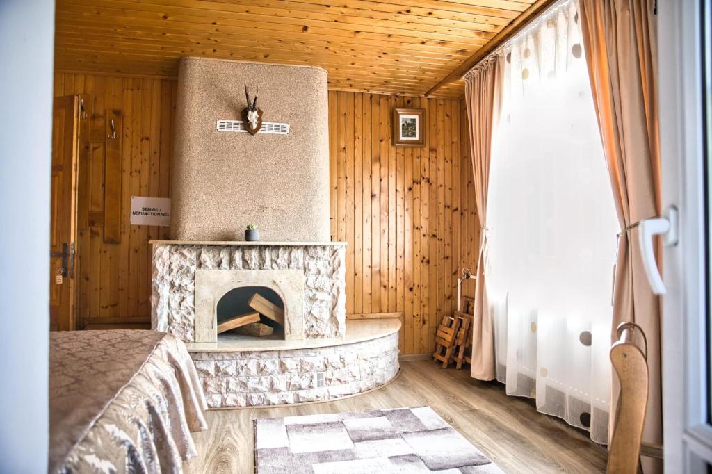 ein Schlafzimmer mit einem Steinkamin in einem Holzzimmer in der Unterkunft Casa Pojorâta in Pojorîta