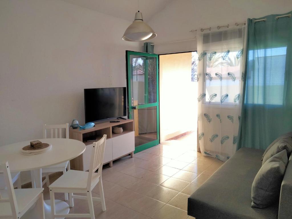 een woonkamer met een bank, een tafel en een tv bij Mirador de Sotavento apartment 8241 in Costa Calma