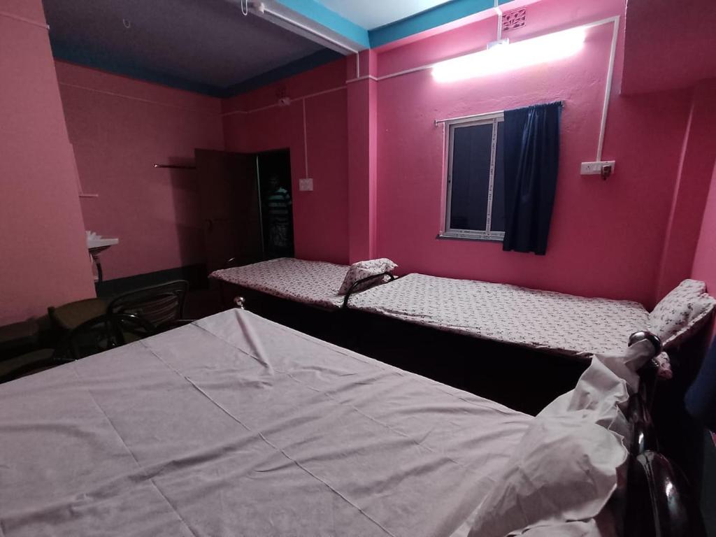Habitación con 2 camas en una habitación rosa en Atithi Nibas Home stay, 