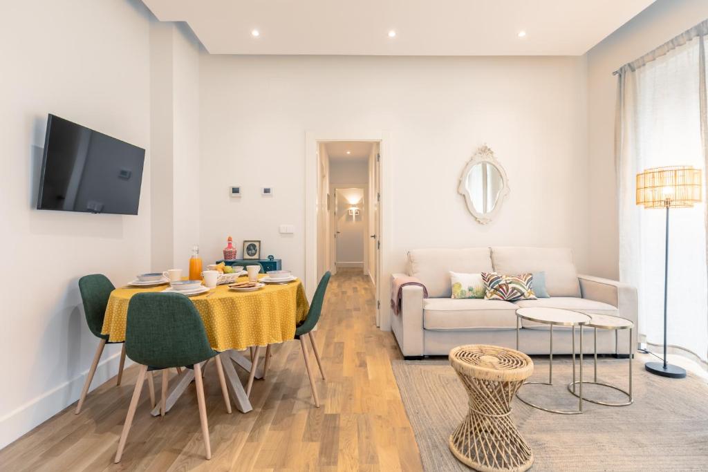 een woonkamer met een tafel en stoelen en een bank bij Magno Apartments Casa del Correo Mayor II in Sevilla