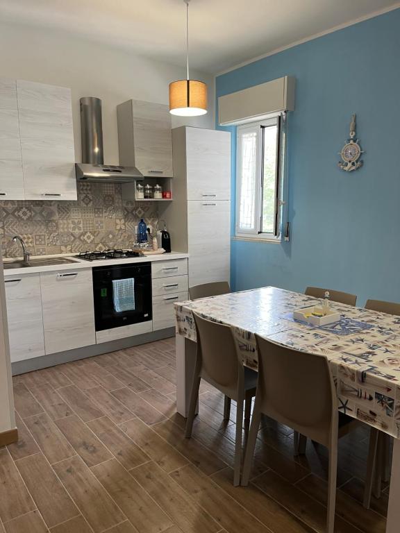 kuchnia ze stołem i krzesłami oraz niebieską ścianą w obiekcie VILLA FRANCA w mieście Fontane Bianche
