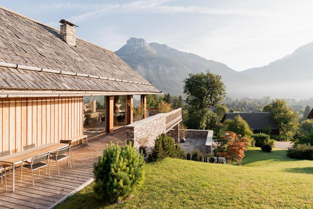 a house with a deck with mountains in the background at Villa Seeblick in Altaussee