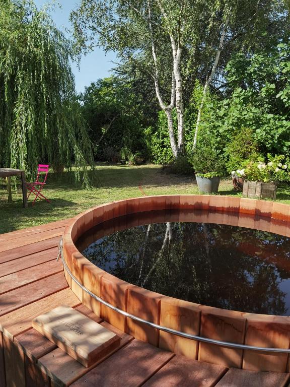 a wooden deck with a pond in the middle of a yard at 2 chambres dans maison familiale jardin et spa in Noisy-le-Roi