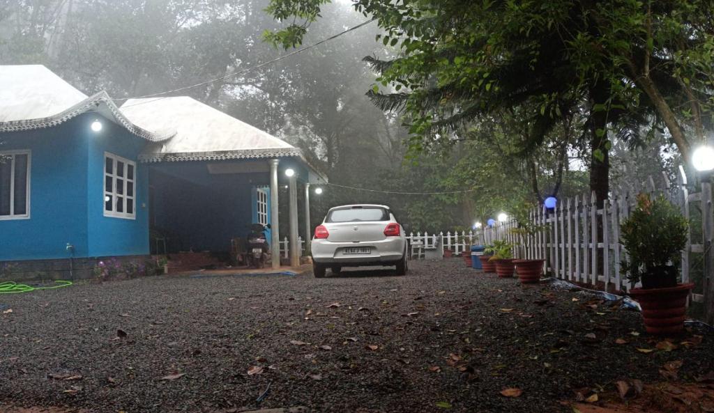 un coche blanco estacionado frente a una casa azul en Noble Homestay en Munnar