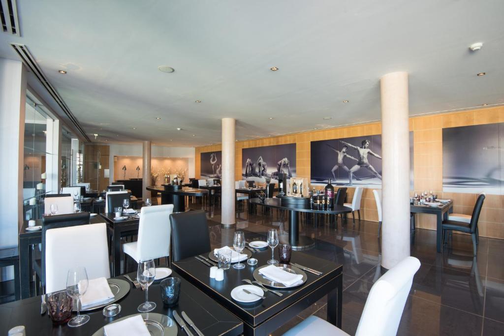 a restaurant with black tables and white chairs at Vila Gale Collection Praia in Albufeira