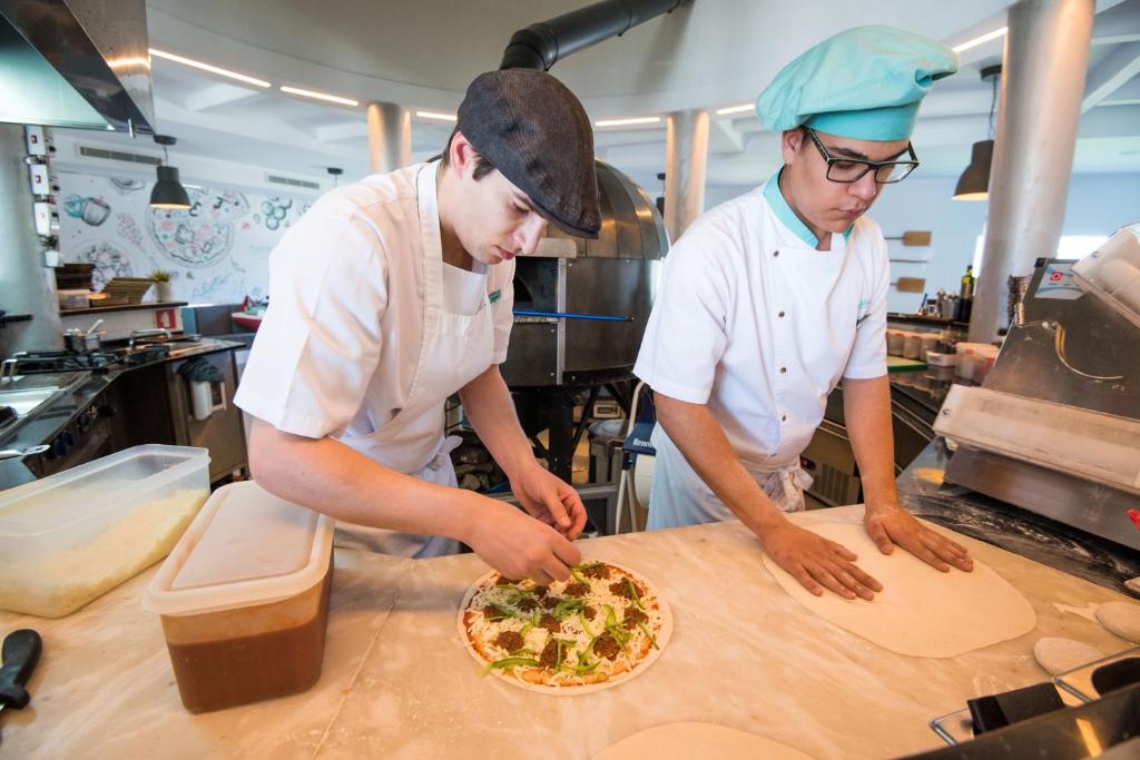 two chefs preparing a pizza in a kitchen at Vila Gale Collection Praia in Albufeira