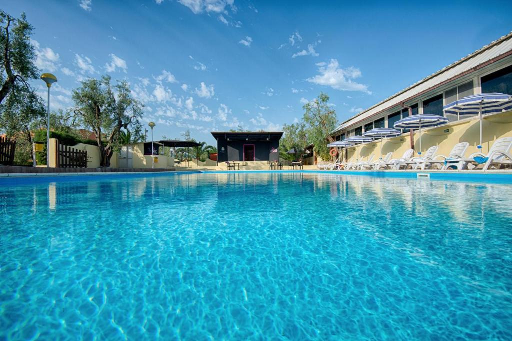 a large swimming pool with chairs and a building at Hotel Palme Gemelle in Vieste