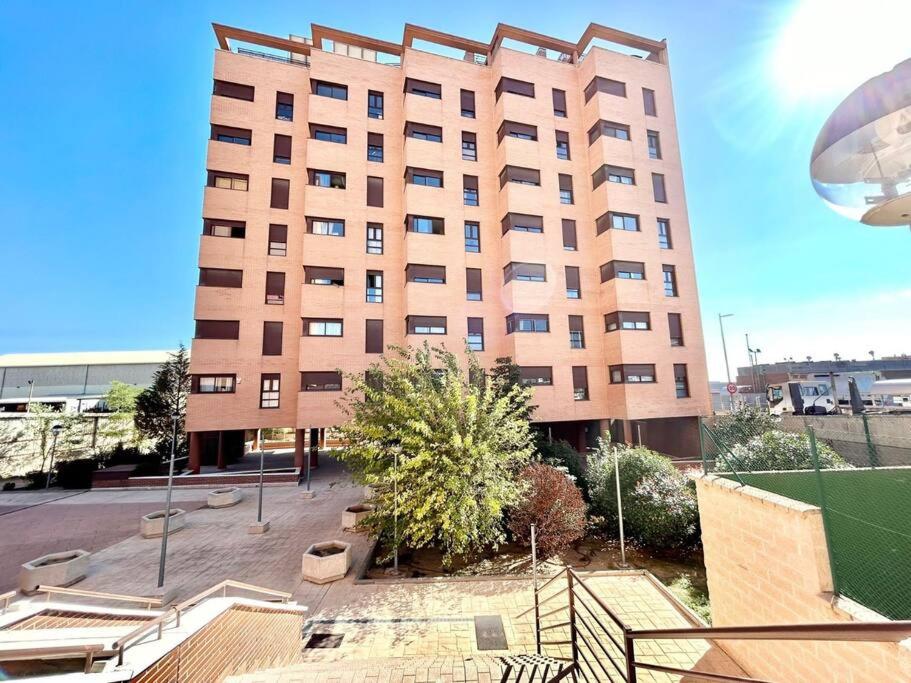 a large building with a tree in front of it at Valleca Tren Sierra Guadalupe 1 in Madrid
