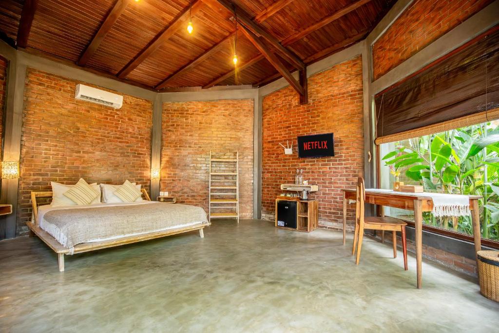 a bedroom with a bed and a brick wall at Pachamama Canggu Bali in Canggu