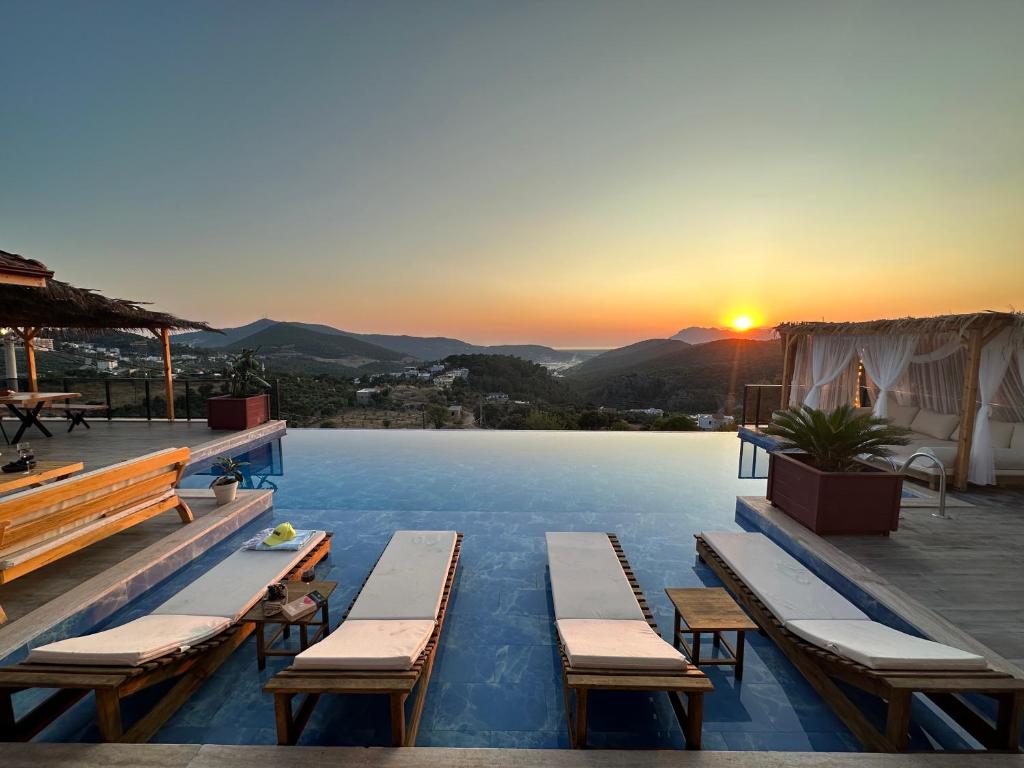 una piscina con bancos y una puesta de sol en el fondo en Villa Luvia, en Kas