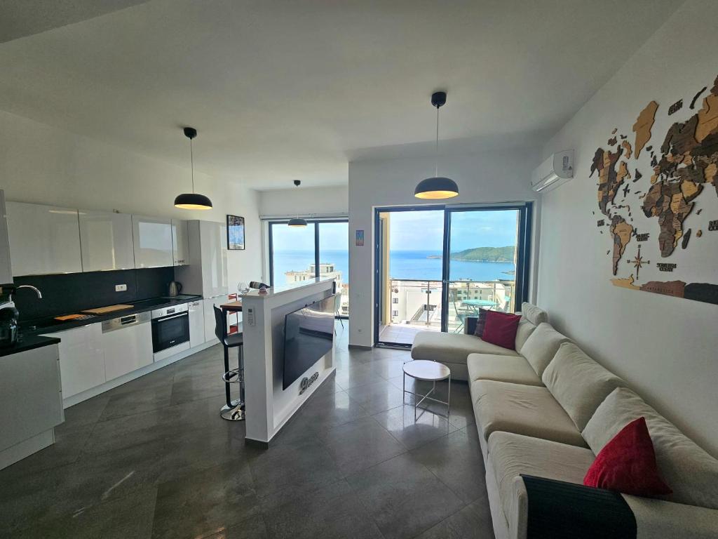 a living room with a couch and a kitchen with the ocean at Modern Top Floor Sea View 3BR with Pools, Spa & Fitness in Becici