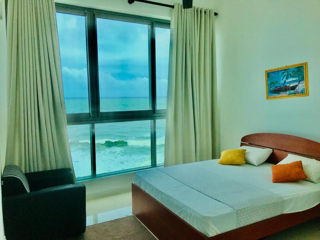 a bedroom with a bed with a view of the ocean at Oceanfront Condos Galle-Apartment L410 A in Galle