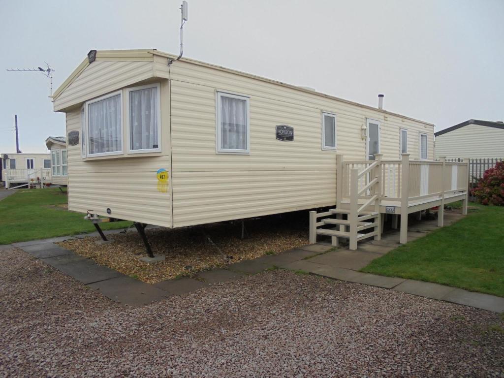 a yellow tiny house with a porch in a yard at 8 Berth on Sealands New Horizon in Ingoldmells