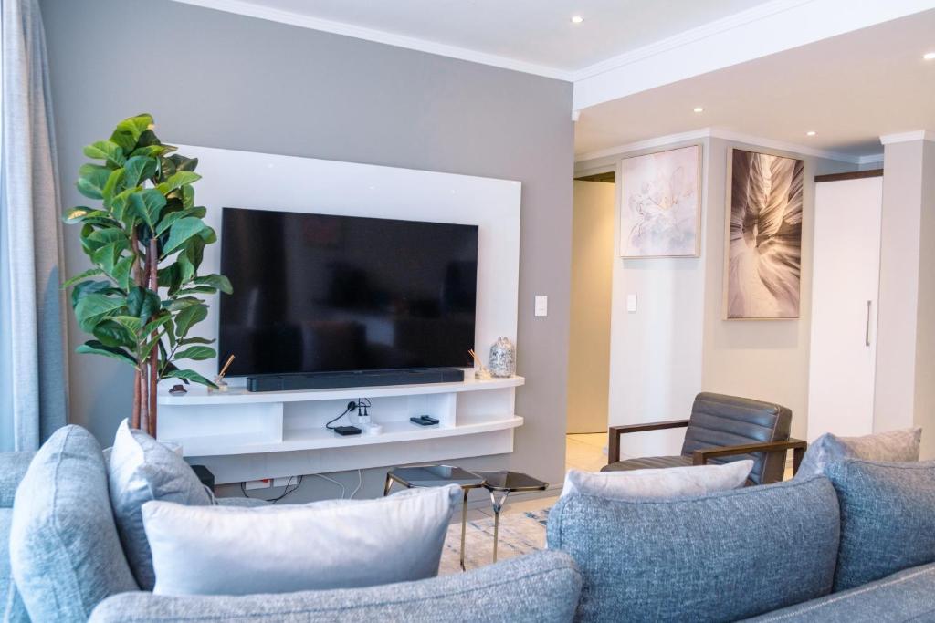 Jordan's Luxe Apartments في جوهانسبرغ: غرفة معيشة مع أريكة وتلفزيون