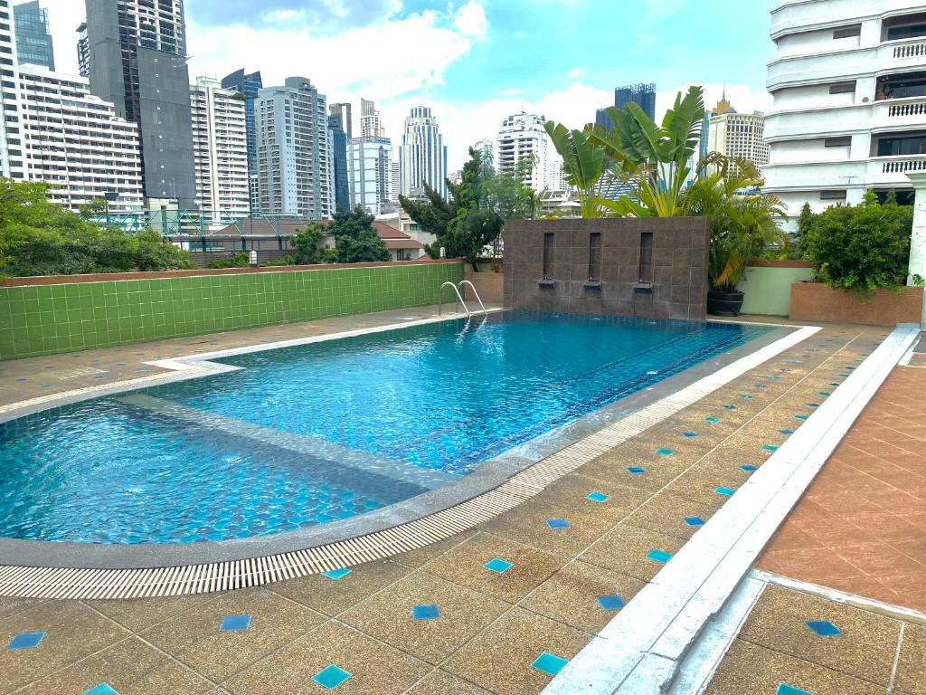 a large swimming pool with a city in the background at Woraburi Sukhumvit Hotel in Bangkok