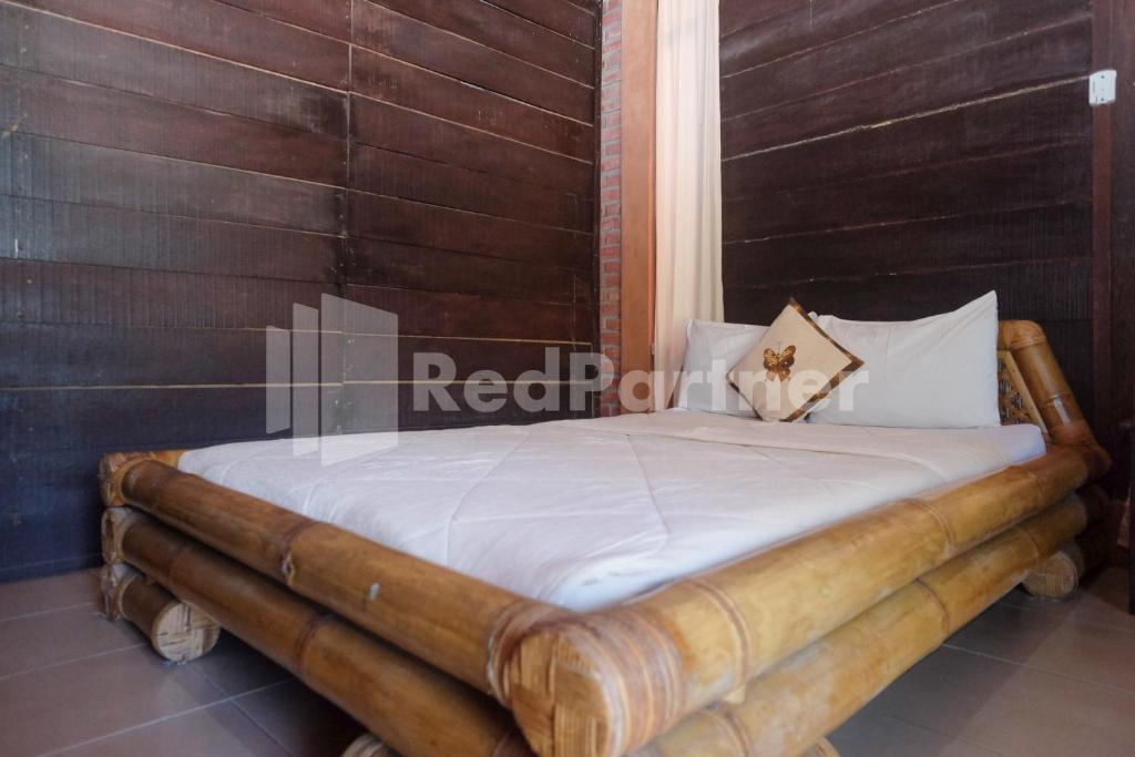 a bed in a room with a wooden wall at Kebon Krapyak Cottage Syariah Mitra RedDoorz near Stadion Maguwoharjo in Yogyakarta