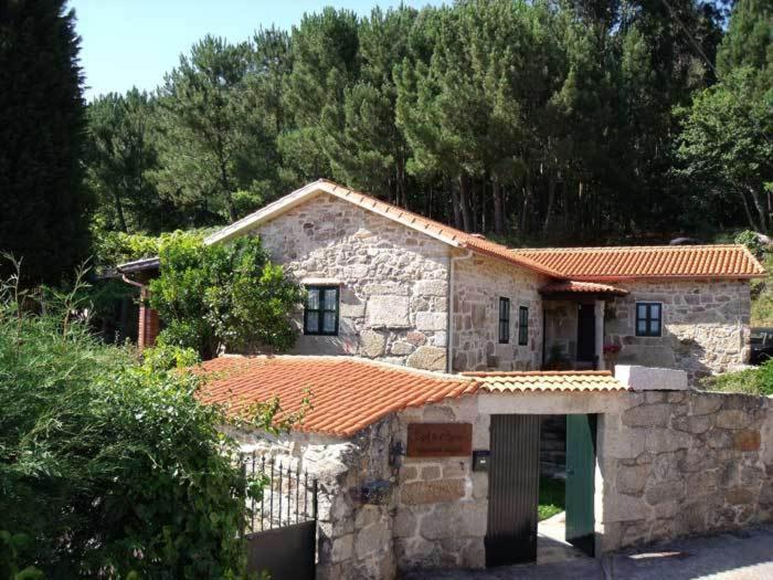 une petite maison en pierre avec un toit orange dans l'établissement Casal de Folgueiras Rias Baixas, à Meis