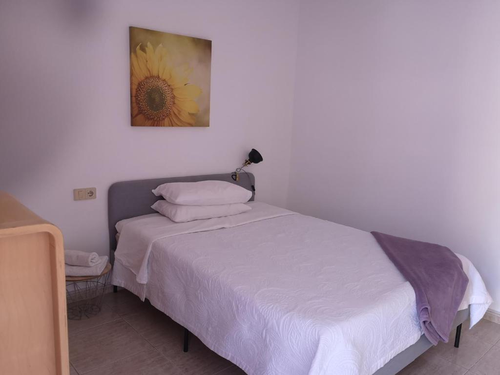 um quarto com uma cama com uma pintura de flores na parede em Acogedoras Habitaciones Privadas zona Costera Wifi em Morro del Jable