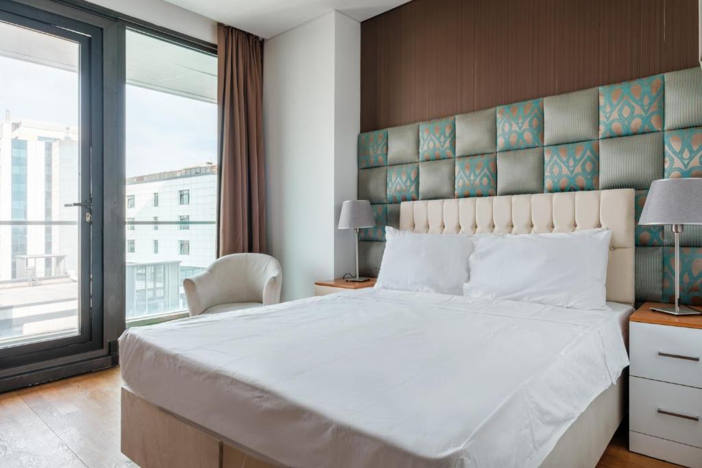 a bedroom with a large white bed and a large window at Studio with City View Balcony 2 min to Metro in Istanbul