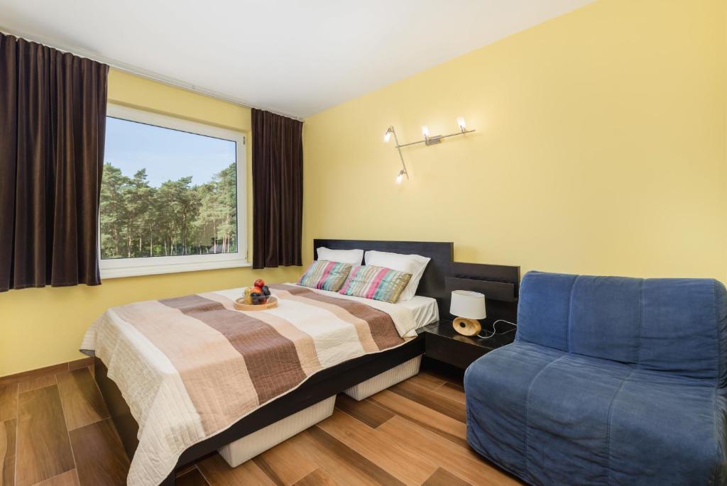 1 dormitorio con 1 cama y 1 silla azul en Spokojny Apartament blisko Plaży - Spacerowa - by Renters en Łukęcin