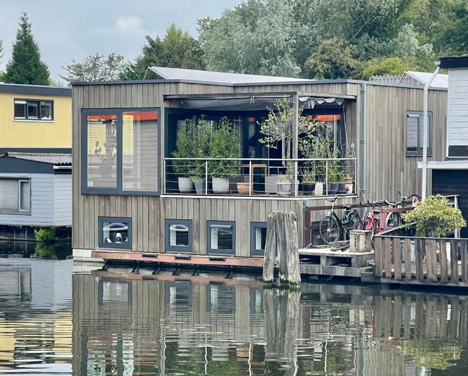 a house on a dock on a body of water at NOVA Houseboat DELUXE Free Bikes in Amsterdam