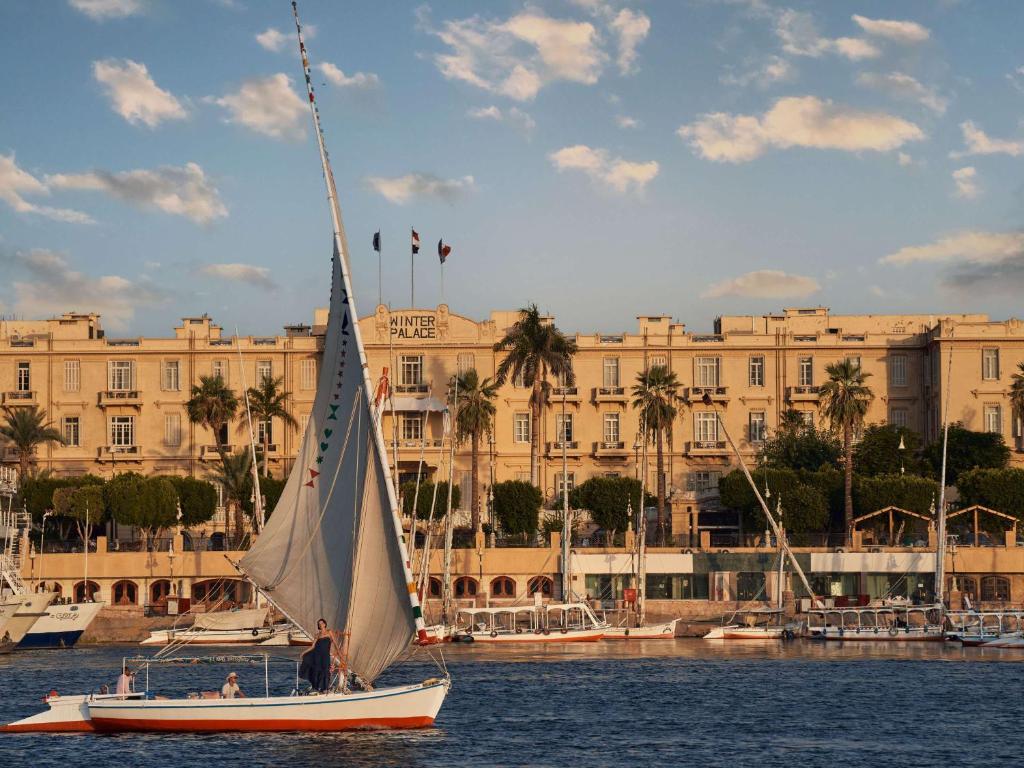 a sail boat in the water in front of a building at Sofitel Winter Palace Luxor in Luxor