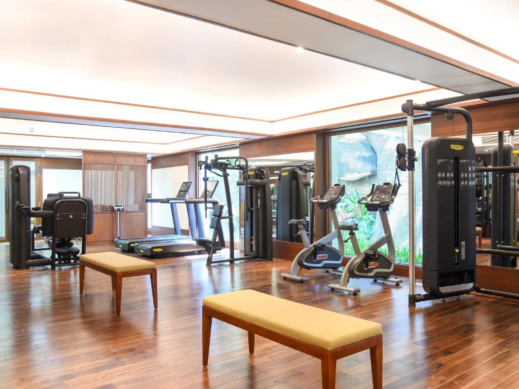 A bright fitness room with cardio machines, weight equipment and wooden benches.